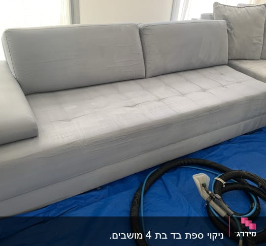 ספה אפורה עם צינור ניקוי על יריעת מגן כחולה